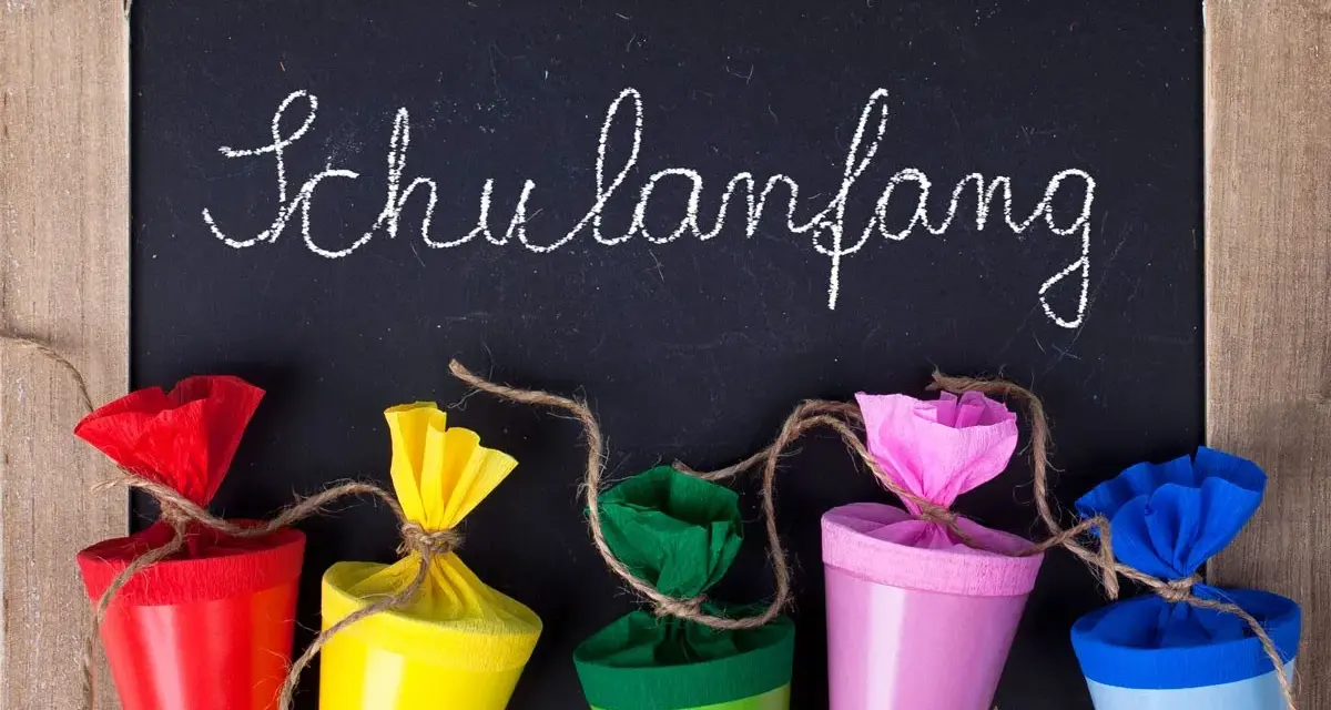 Bunte Schultüten vor einer Tafel mit "Schulanfang" für die Einschulung Hessen 2025.