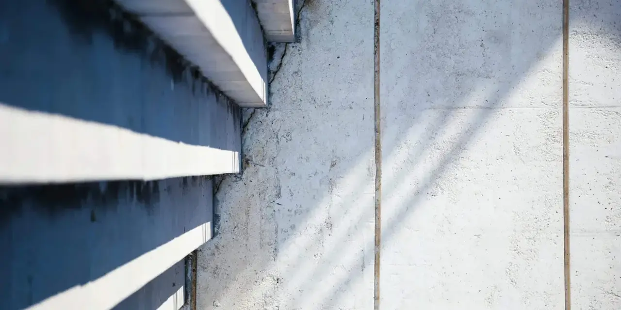 Ombre et lumière sur un mur en béton cellulaire, texture brute et lignes architecturales.