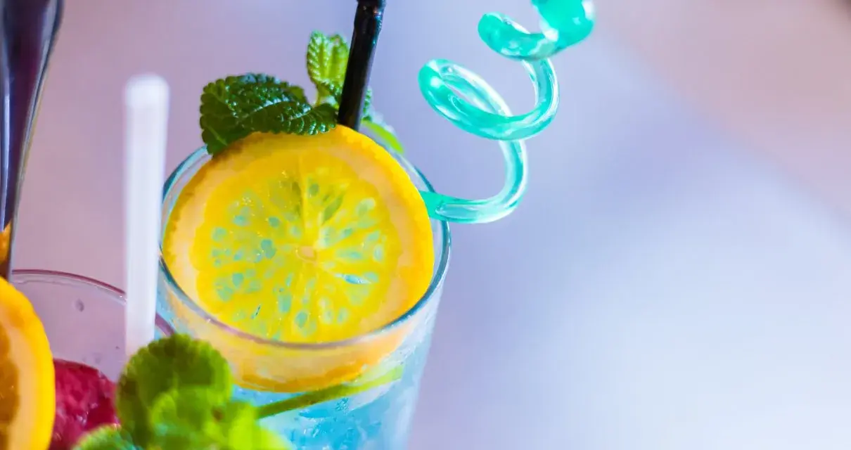 Orzeźwiający drink z sokiem żurawinowym, ozdobiony plasterkiem cytryny i listkami mięty. Idealny na upalne dni.