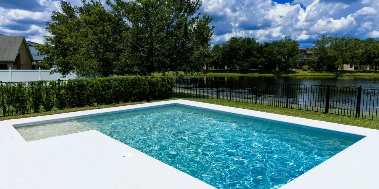 Agua de piscina blanquecina, cristalina y refrescante, con reflejos del cielo azul y nubes blancas. Un oasis de paz.