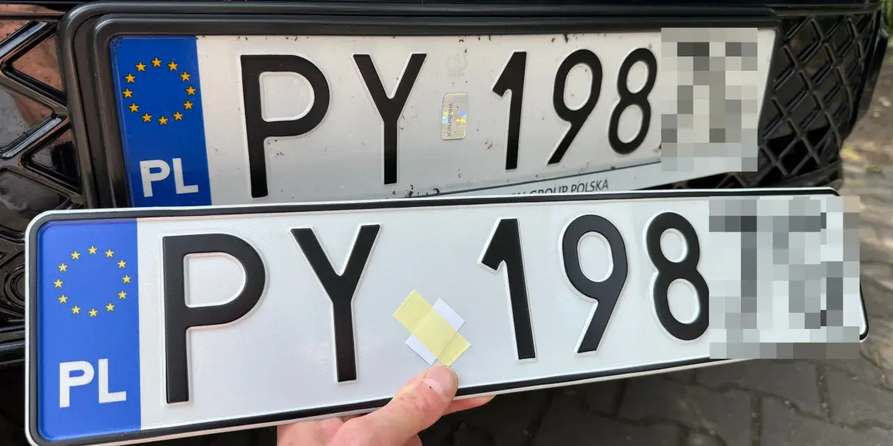 Dwie polskie tablice rejestracyjne PY 198. Jedna jest zamontowana na samochodzie, druga trzymana w ręku.