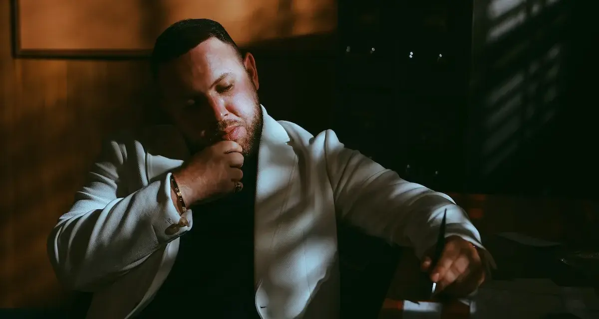 Louis Villain, w wieku około 40 lat, w białej marynarce, zamyślony przy biurku.
