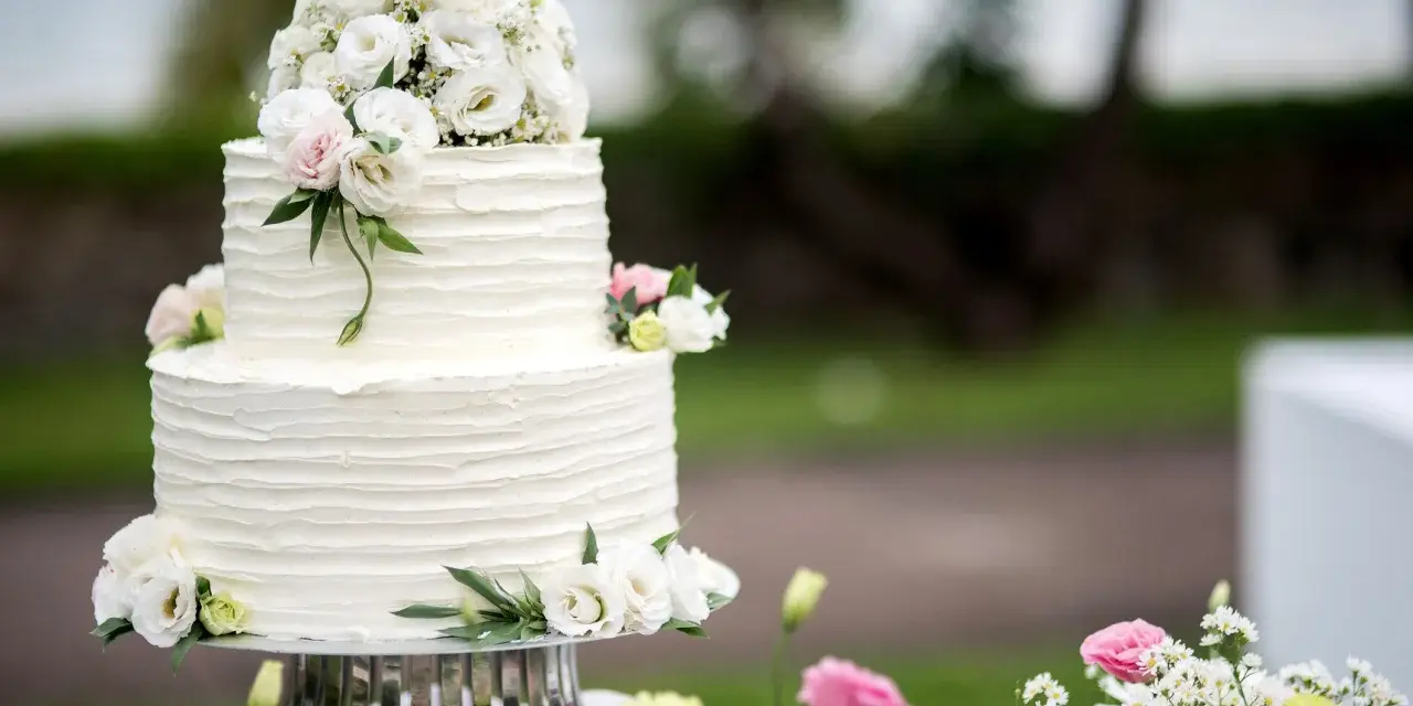 Elegancki, dwupiętrowy tort weselny ozdobiony bukietem białych i różowych, **jakie żywe kwiaty na tort** dodają mu uroku.