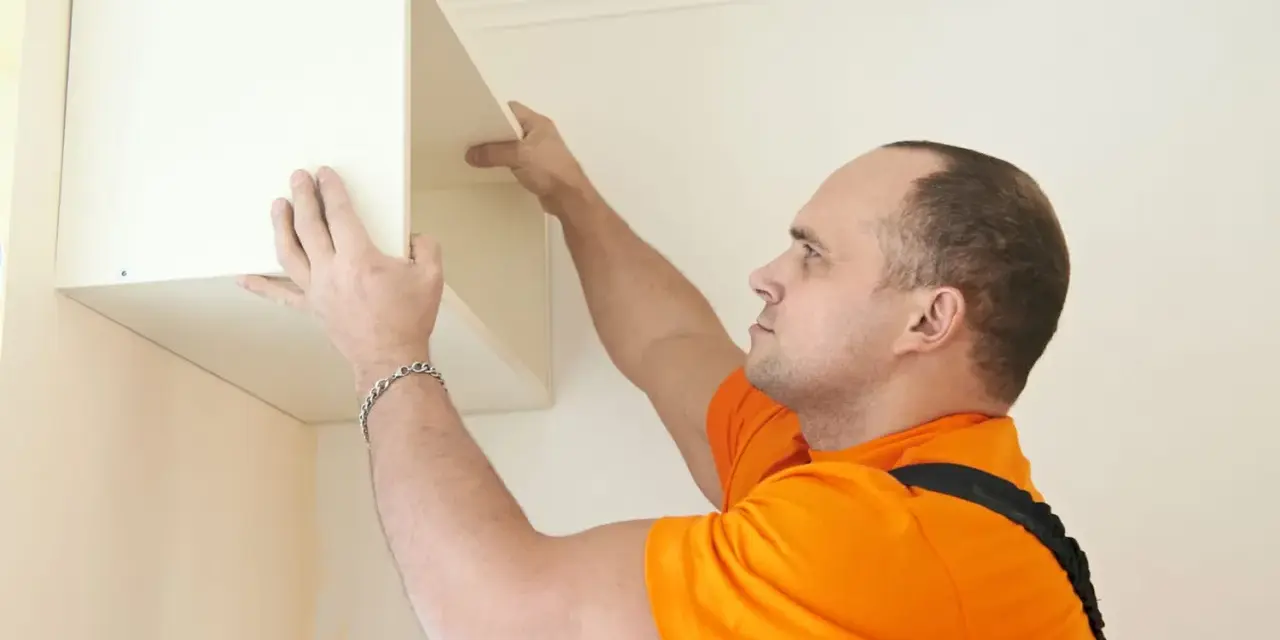 Un homme installe une étagère murale, une étape cruciale pour fixer meuble lourd sur placo.
