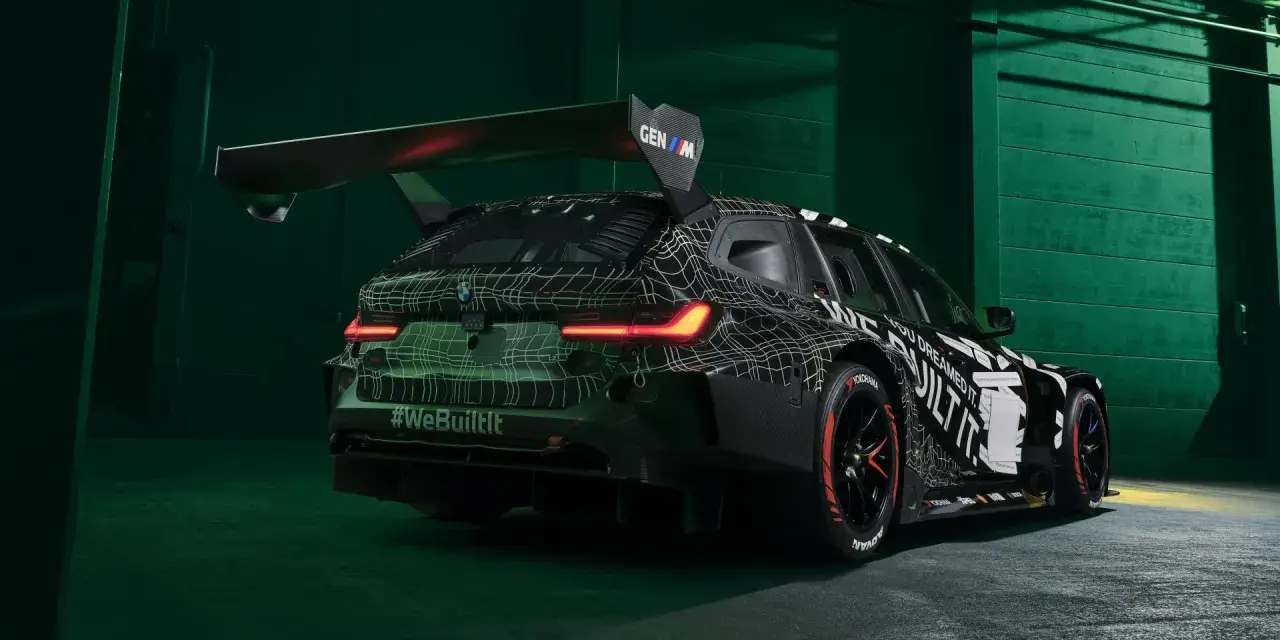 Wyścigowe BMW M3 2025 w kamuflażu, z ogromnym spojlerem i agresywnym dyfuzorem.