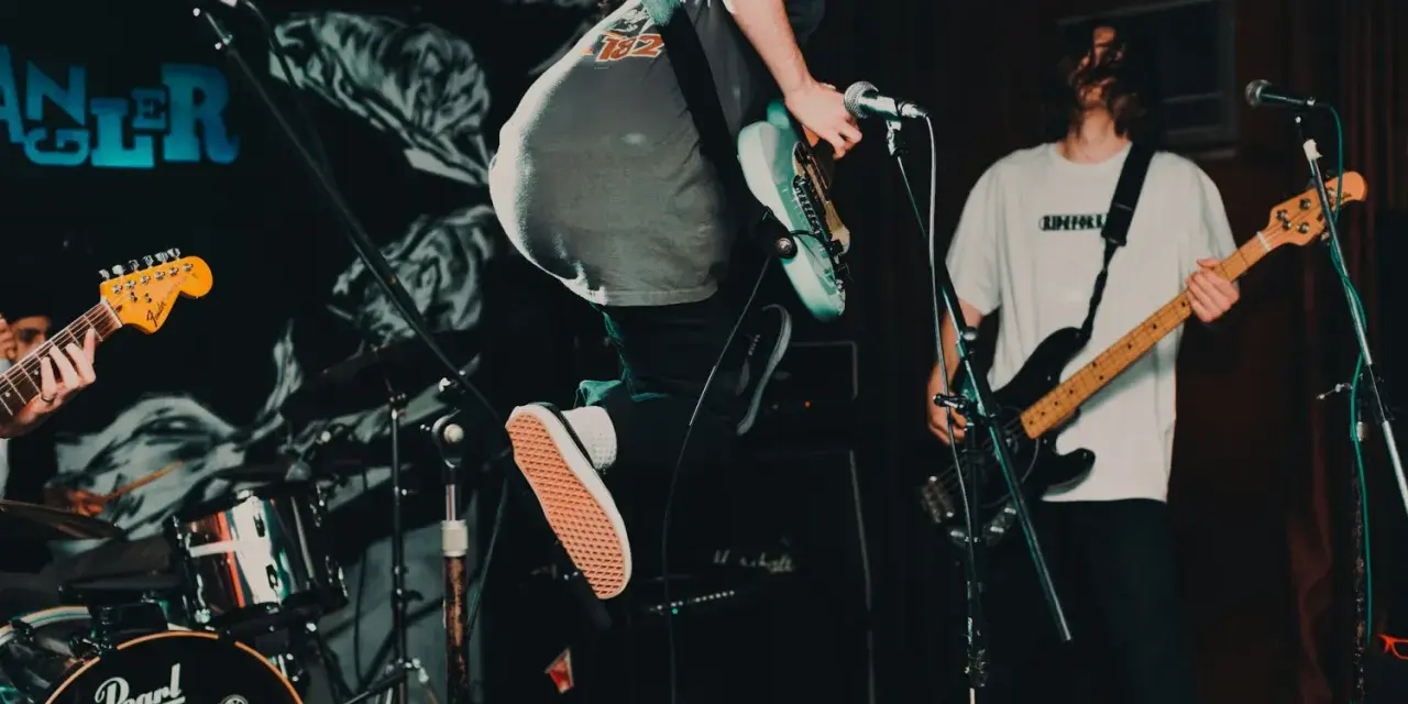 Ein Gitarrist springt auf der Bühne, während ein Bassist spielt. Das ist Rockmusik in Aktion!