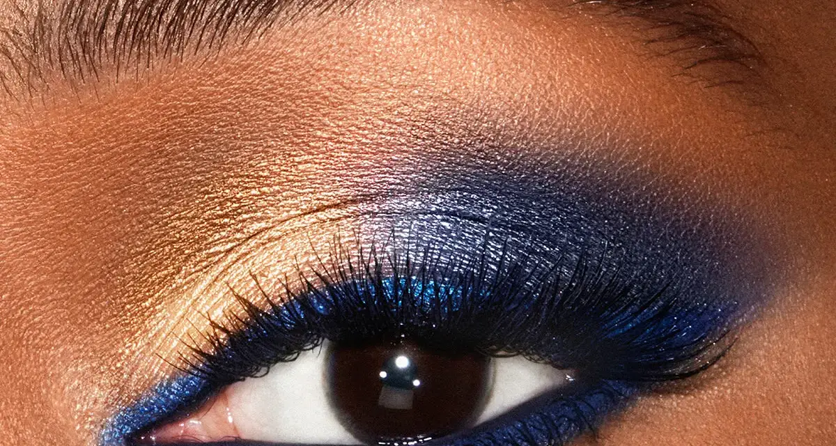 Un œil aux smoky eyes bleus intenses, rehaussé de fard doré et de paillettes. Un regard captivant.