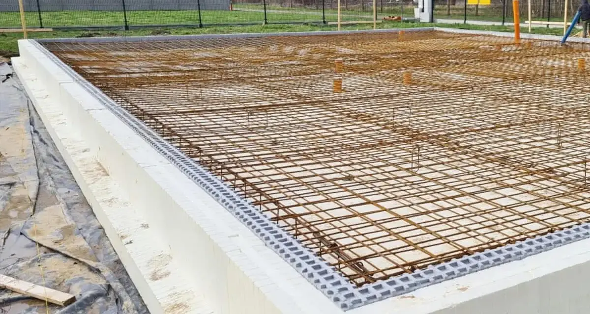 Siatka zbrojenia na fundamencie z białych bloczków styropianowych, gotowa do zalania betonem.