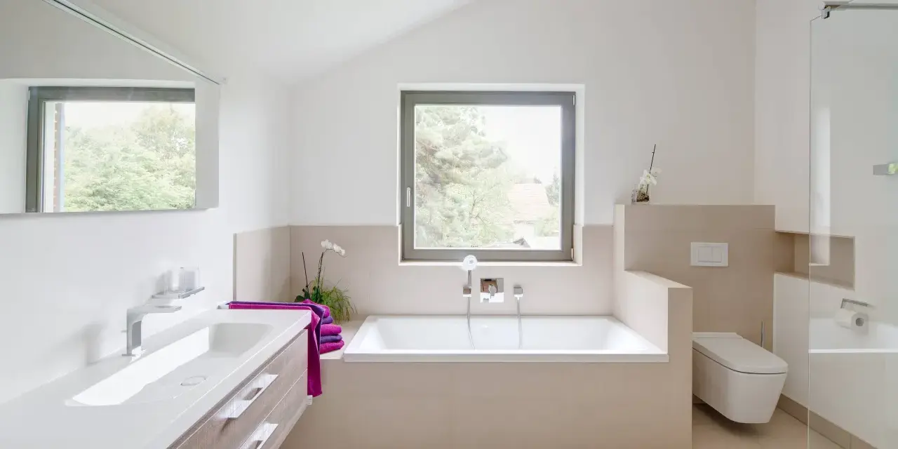 Salle de bain moderne avec baignoire, lavabo, douche vitrée et toilette suspendue.