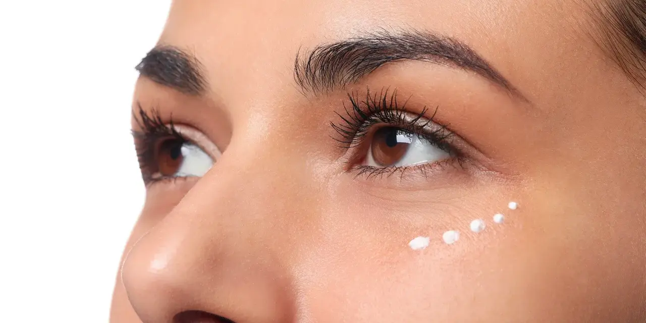 Application de crème hydratante sous les yeux, parfaite pour le maquillage hivernal.