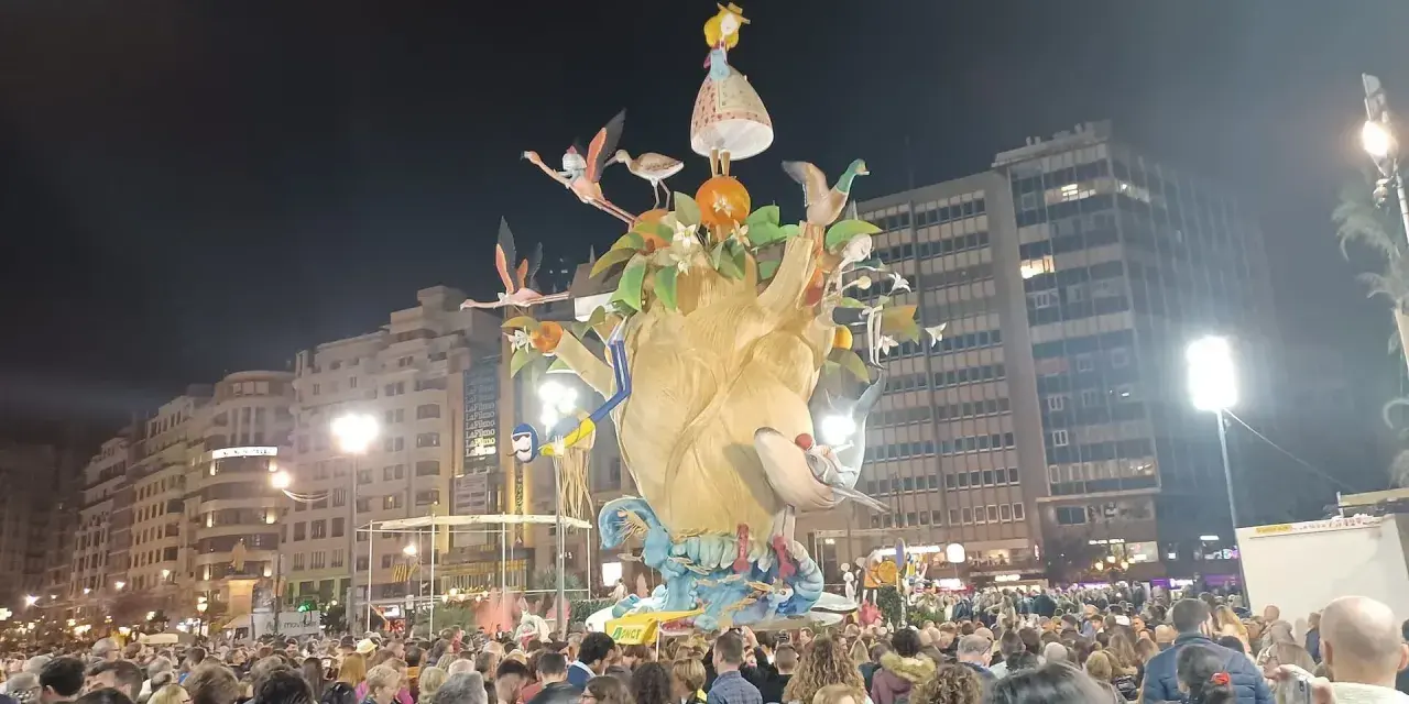 La foule admire une immense sculpture colorée, une scène typique du déroulement des Fallas de Valencia, avec des flamants roses et une petite fille perchée en haut.