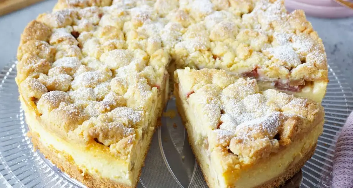 Ein saftiger Rhabarberkuchen mit Puddingfüllung und Streuseln, bestäubt mit Puderzucker.