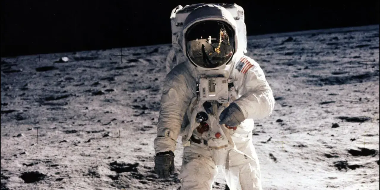 Un astronaute sur la Lune, le 20 juillet 1969. Le reflet dans son casque montre la Terre et d'autres astronautes.