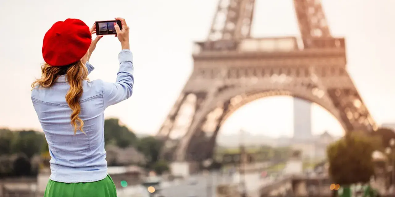 Mujer con boina roja toma foto de la Torre Eiffel. ¡Ideas de qué ver en París!