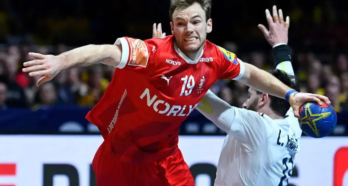 Mathias Gidsel w czerwonej koszulce z numerem 19, w akcji podczas meczu piłki ręcznej, walczy o piłkę.