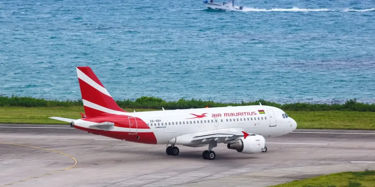 Samolot Air Mauritius na pasie startowym, w tle turkusowe morze i łódź. Twoje loty na Mauritius właśnie się zaczynają!