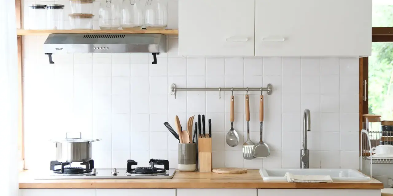 Diseños de cocinas pequeñas y sencillas: encimera de madera, campana extractora, utensilios colgados y un fregadero blanco.