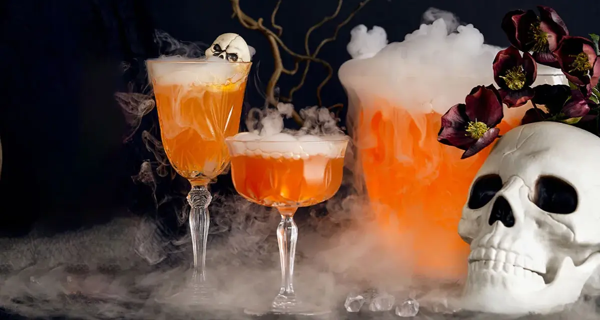Två orangea drinkar med skum och en dödskalle, perfekt för en kuslig halloween-kväll.