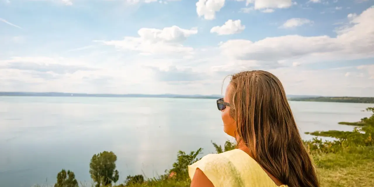 Kobieta w żółtej bluzce podziwia widok na Balaton. Wspaniałe chmury na niebie, idealne miejsce, gdzie nad Balaton.
