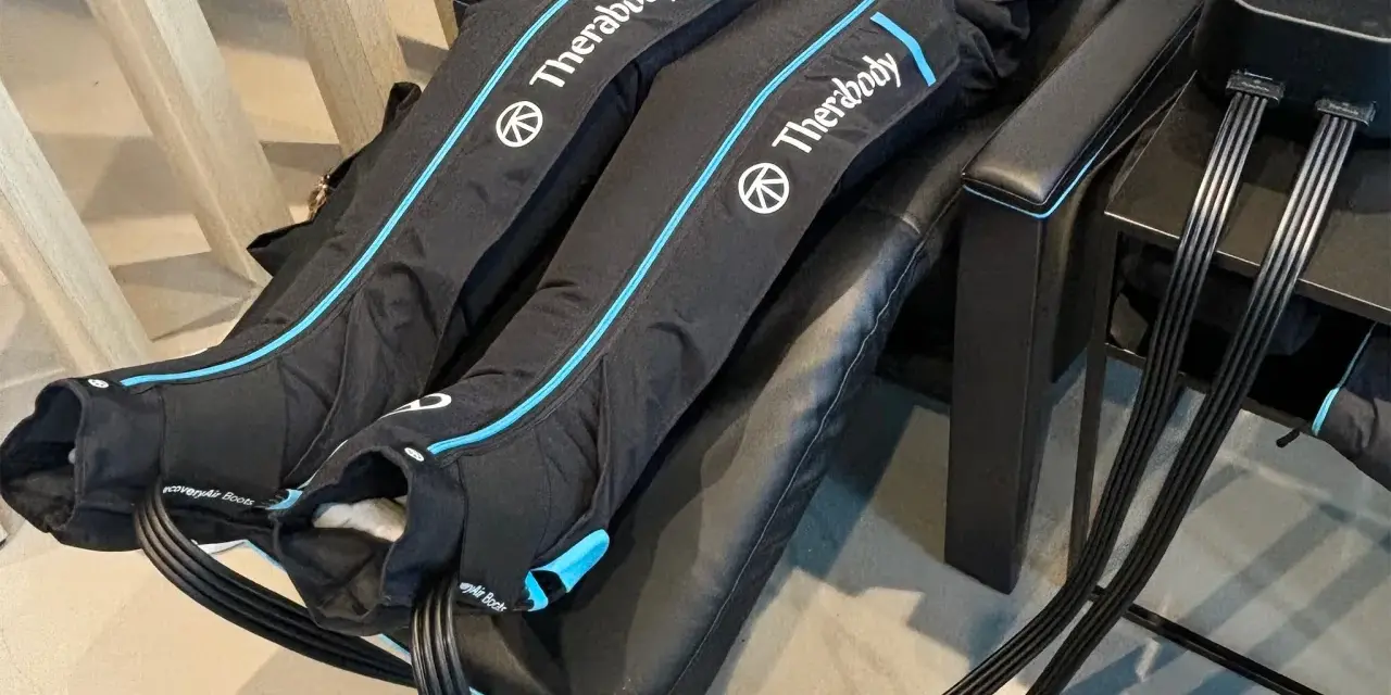 Are leg compression massagers good for you? This image shows a person using Therabody recovery boots, which are leg compression massagers, for a relaxing massage.