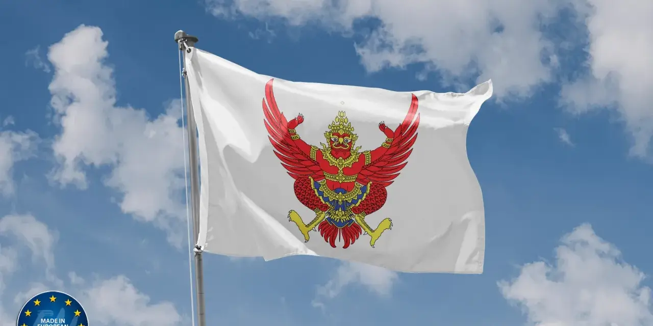 Biała flaga z wizerunkiem czerwonego Garudy, symbolu Tajlandii, powiewa na tle błękitnego nieba z chmurami.