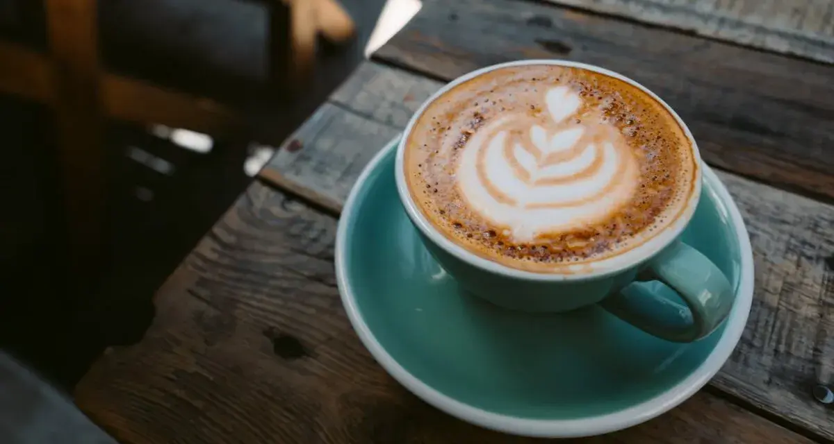 Aromaticzna kawa ristretto z pianką latte art na drewnianym blacie. Idealny poranek.