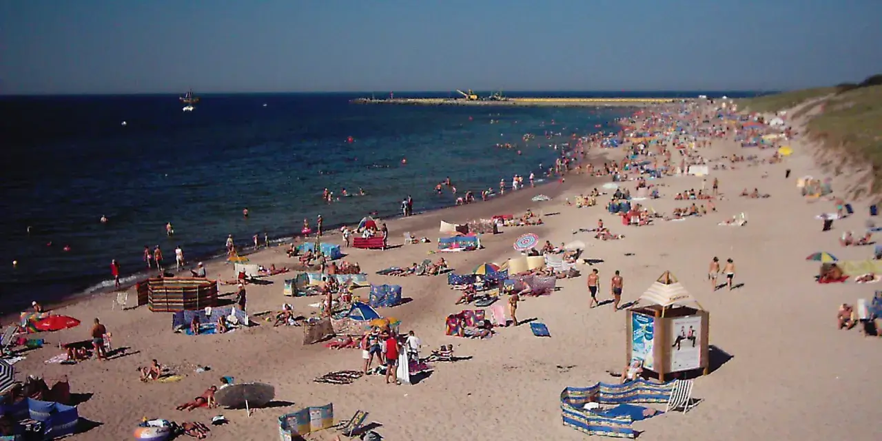 Tłum plażowiczów na piaszczystej plaży, woda i niebo. Czy to Darłówko wschodnie czy zachodnie?