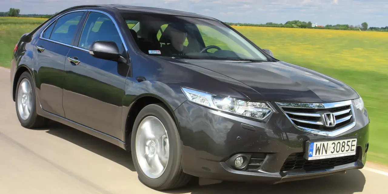 Ciemnoszary sedan Honda Accord, idealny auto do 40 tys., jedzie przez pola rzepaku.