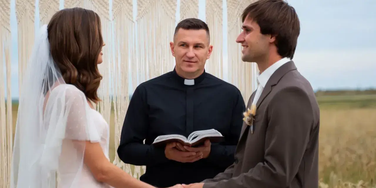 Para młoda trzymająca się za ręce podczas ceremonii ślubnej, z księdzem trzymającym Biblię.