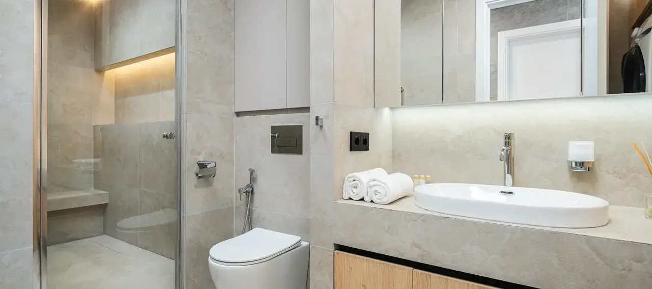 Modernt kaklat badrum med dusch, toalett och handfat. Ljus och stilren design.
