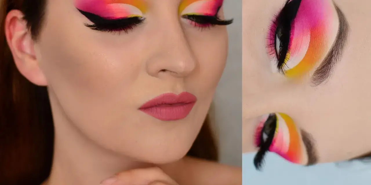 Oczy z wyrazistym makijażem cut crease w odcieniach różu, pomarańczy i żółci. Czarne kreski i długie rzęsy podkreślają spojrzenie.