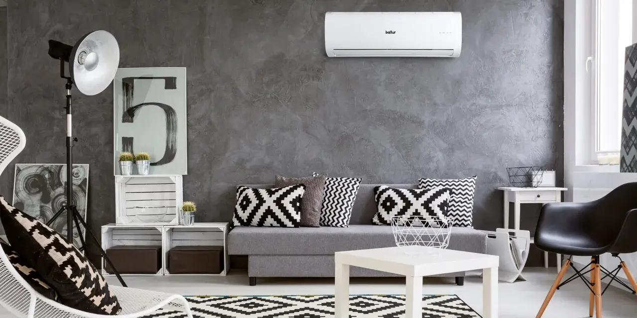 Un moderno soggiorno con divano grigio, cuscini geometrici e un **condizionatore** a parete. Il significato è comfort e stile.