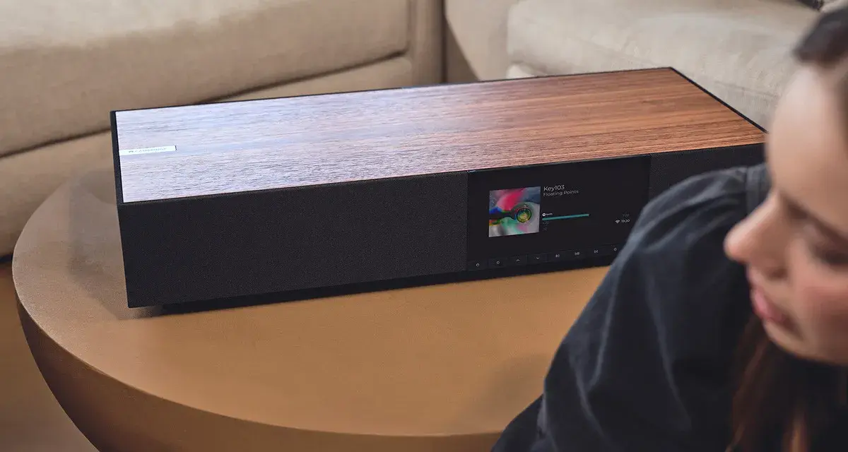 Elegancki Cambridge Audio One z drewnianym blatem i ekranem odtwarza muzykę.