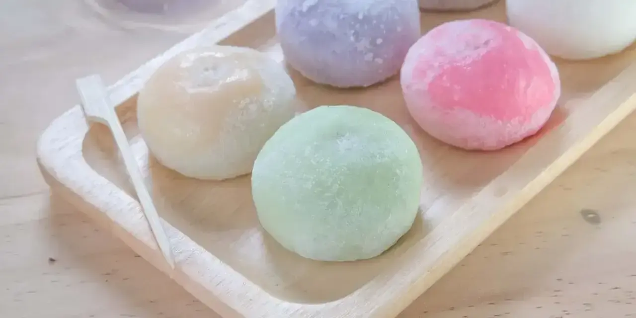 Kolorowe mochi na drewnianej tacce. Chcesz wiedzieć, jak zrobić mochi? Te słodkie kuleczki wyglądają pysznie!