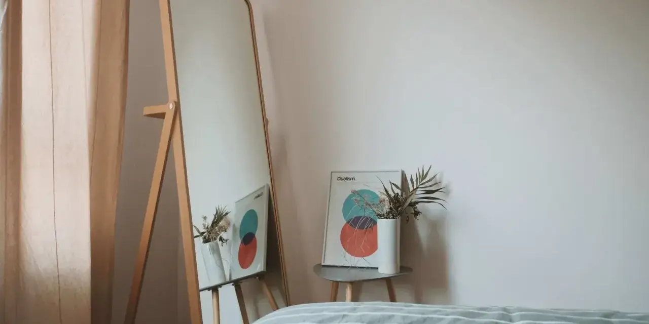 Lustro odbija plakat z kołami i wazon z suszonymi kwiatami. To inspiracja do stworzenia własnej konmari listy porządków.