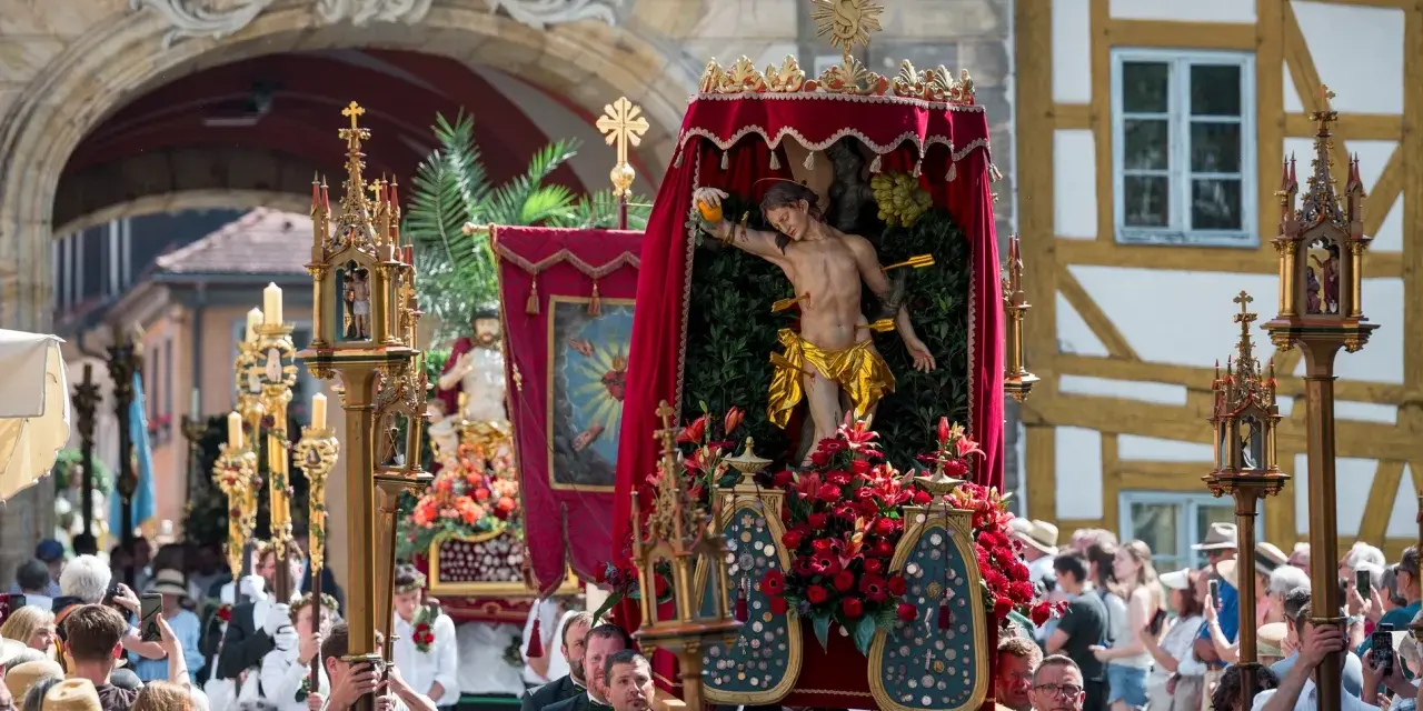 Prozession mit Jesus-Figur und Blumen. Fronleichnam ist ein gesetzlicher Feiertag, an dem solche Umzüge stattfinden.