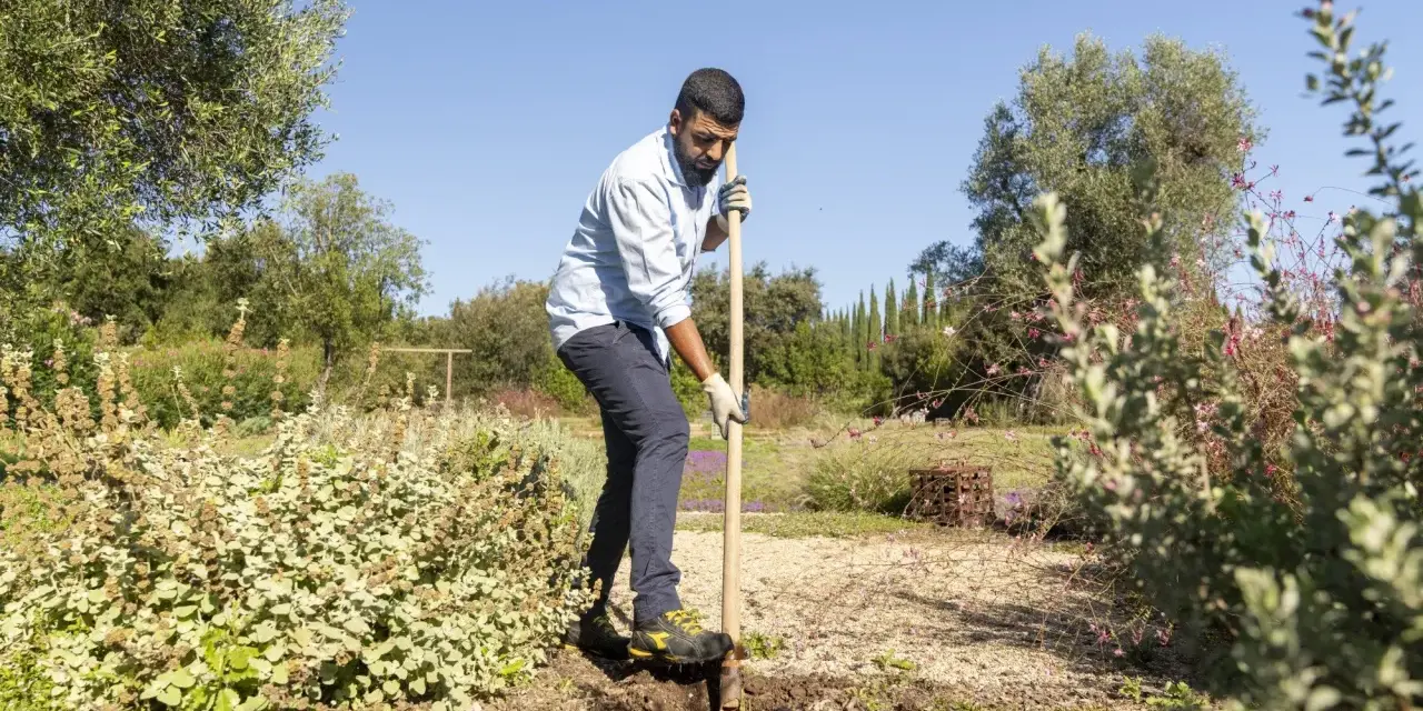 Uomo con pala in un giardino, forse per preparare il terreno con greenex nf dosaggio.
