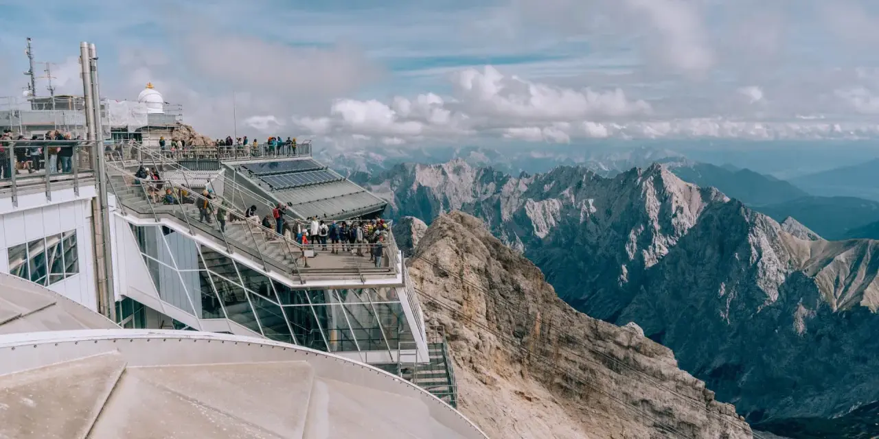 Tłum turystów na tarasie widokowym Zugspitze, najwyższego szczytu Niemiec, podziwia alpejskie krajobrazy.