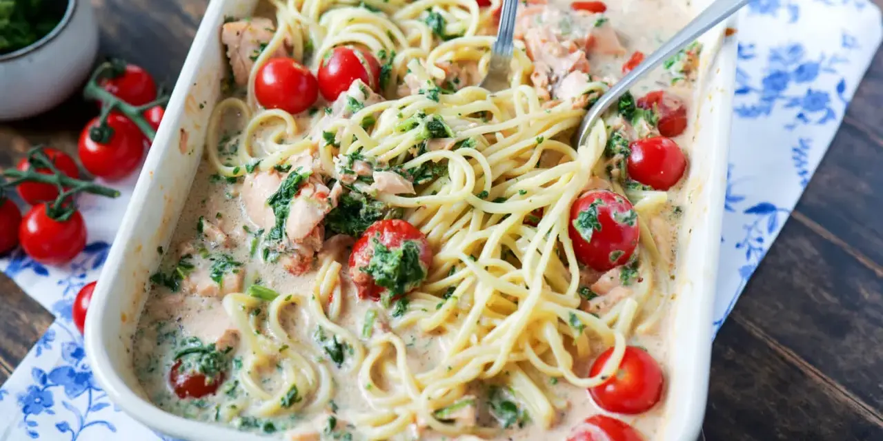 Cremige Lachs Spinat Pasta mit Kirschtomaten in einer Auflaufform, serviert mit zwei Gabeln.