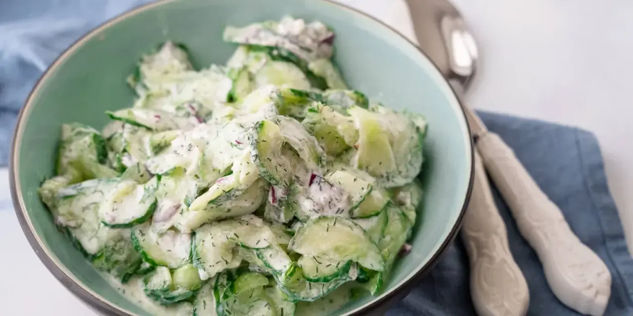 Frischer gurkensalat mit saurer sahne und Dill, garniert mit roten Zwiebeln, in einer Schüssel serviert.