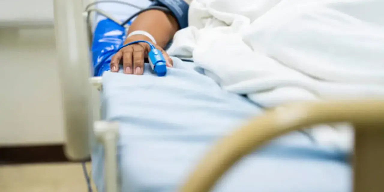 Paciente en cama de hospital con oxímetro en el dedo, indicando la necesidad de permiso por enfermedad.