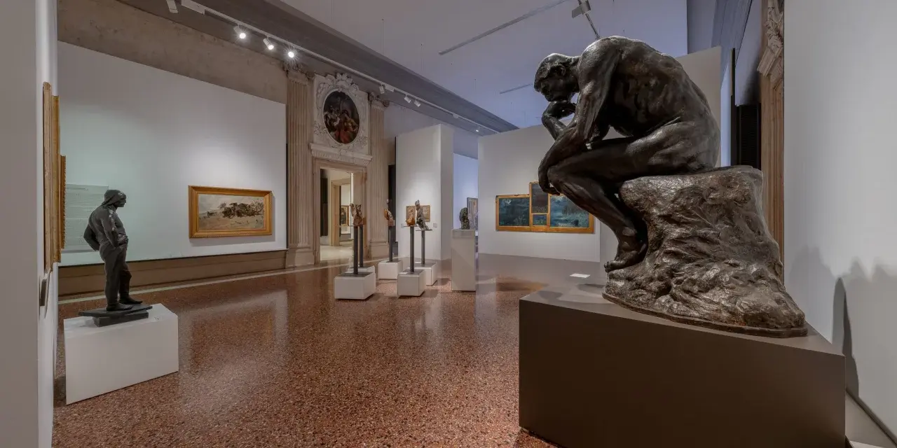 Il Pensatore di Rodin in una sala espositiva, forse a Venezia ca Pesaro, riflette sul significato dell'arte.