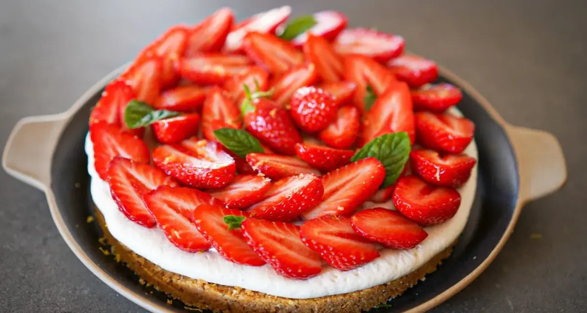 Tarte aux fraises mascarpone, une gourmandise estivale recouverte de fruits rouges frais et de feuilles de menthe.