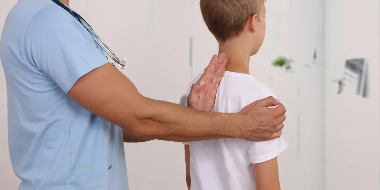 Lekarz bada chłopca, sprawdzając jego postawę. Może to być część diagnostyki zespołu Marfana objawy.