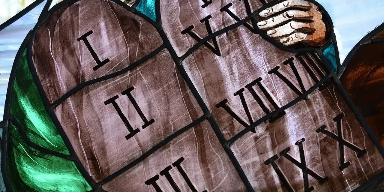 Witraż przedstawia kamienne tablice z wyrytymi cyframi rzymskimi, symbolizujące dekalog przykazania. Widoczne są cyfry I, II, III, IV, V, VI, VII, VIII, IX, X.