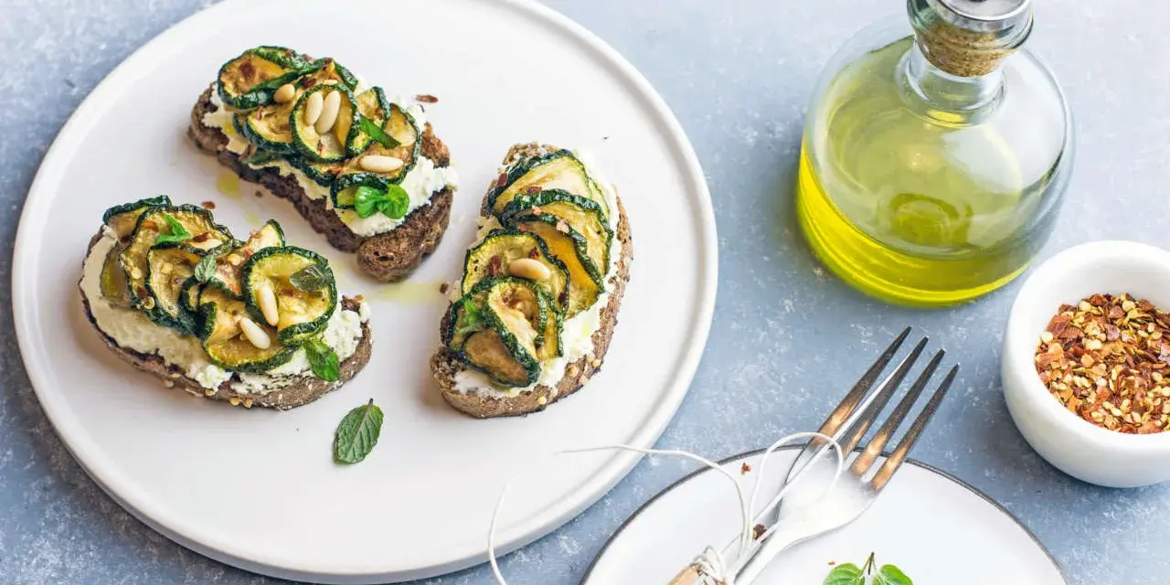 Bruschetta con zucchine grigliate, ricotta e pinoli, condita con un filo d'olio.