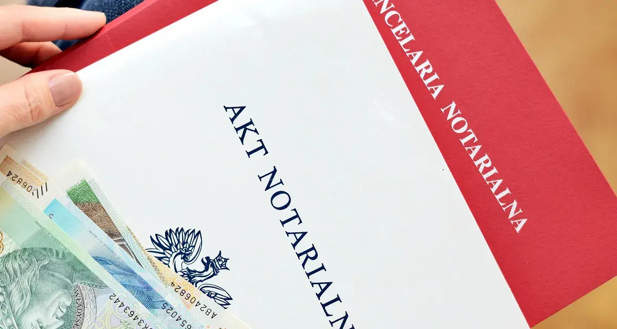 Akt notarialny i polskie banknoty w dłoni.