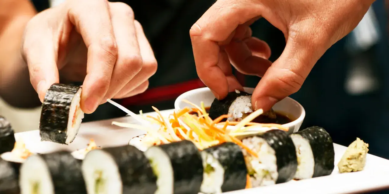 Ręce zanurzają sushi w sosie sojowym. Czy sushi można jeść na drugi dzień? To zależy od świeżości składników i sposobu przechowywania.