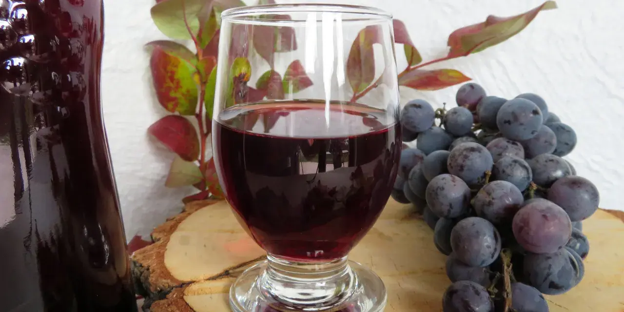 Wino z ciemnych winogron, kieliszek, kiść winogron i butelka. Idealne na przepis na wino z ciemnych winogron.