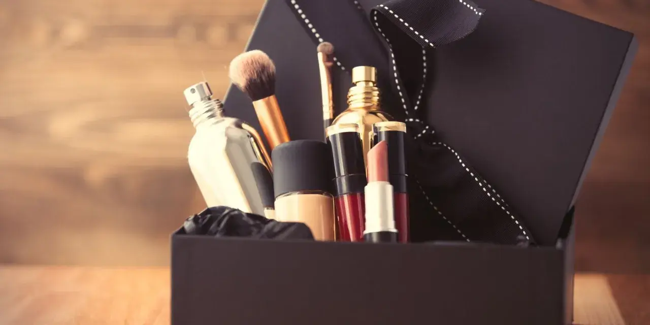 Schwarze Geschenkbox mit Kosmetikartikeln wie Parfüm, Lippenstift und Make-up-Pinseln.